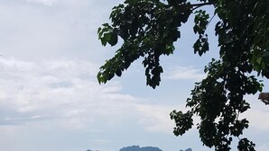 Un área de estar al aire libre con madera y vista al mar y a islas distantes.