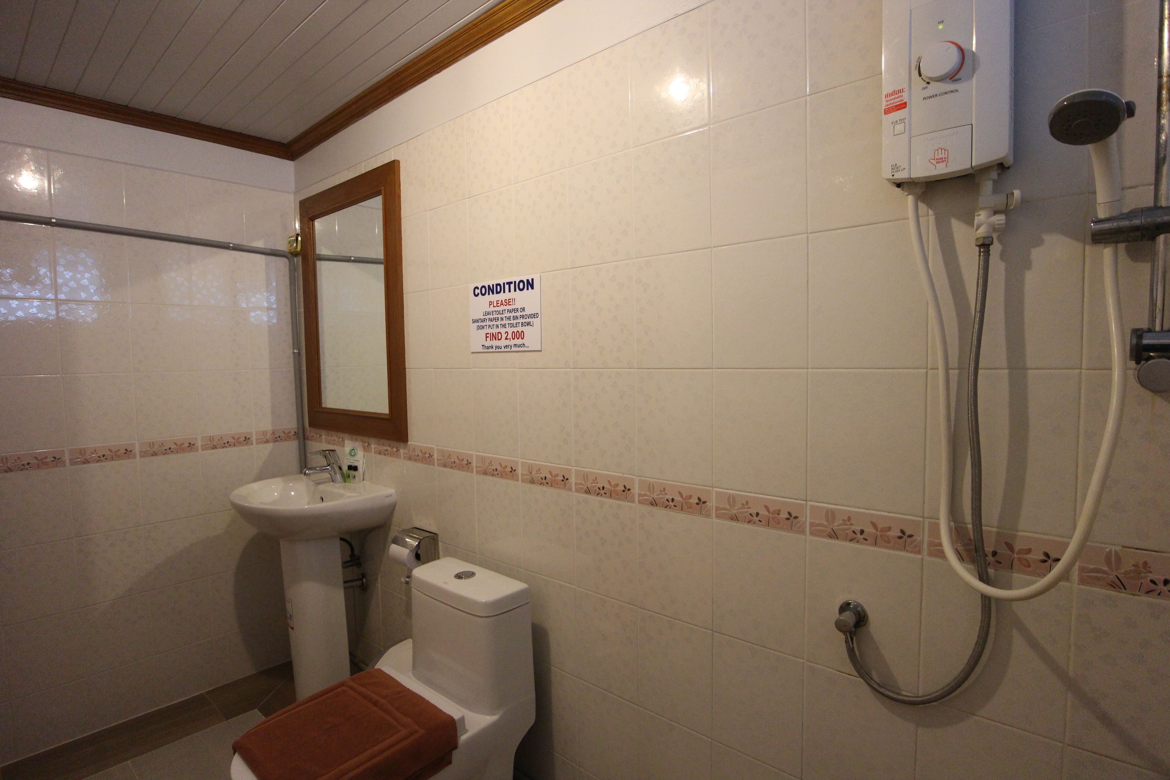 A bathroom with a sink, toilet, and shower. There is a sign on the wall that reads "CONDITION PLEASE!".