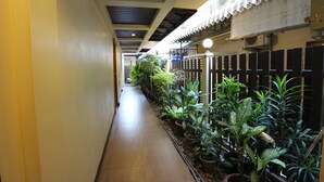 A narrow corridor with a tiled floor, flanked by potted plants and a white fence. - JJ Residence (Ko Phi Phi)
