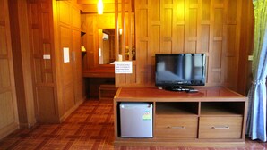 A compact room with wooden paneling, a television on a wooden stand, a small refrigerator, and a bench. - JJ Residence (Ko Phi Phi)
