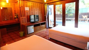 A hotel room with a bed, a TV, a small fridge, and a view of the outside. - JJ Residence (Ko Phi Phi)