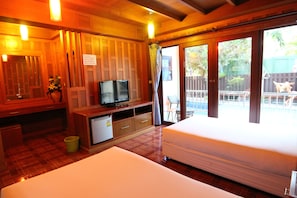 A hotel room with a bed, a TV, a small fridge, and a view of the outside. - JJ Residence (Ko Phi Phi)