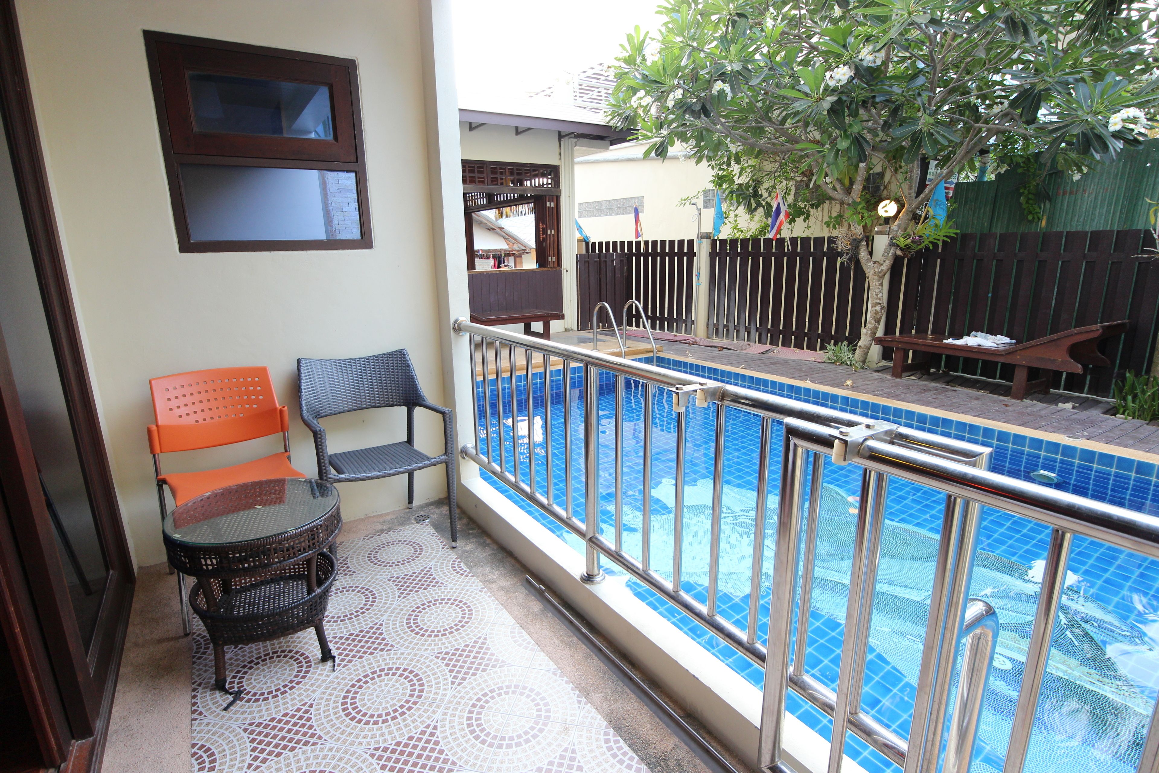 Un balcon avec une piscine, deux chaises, une table et un banc en bois.