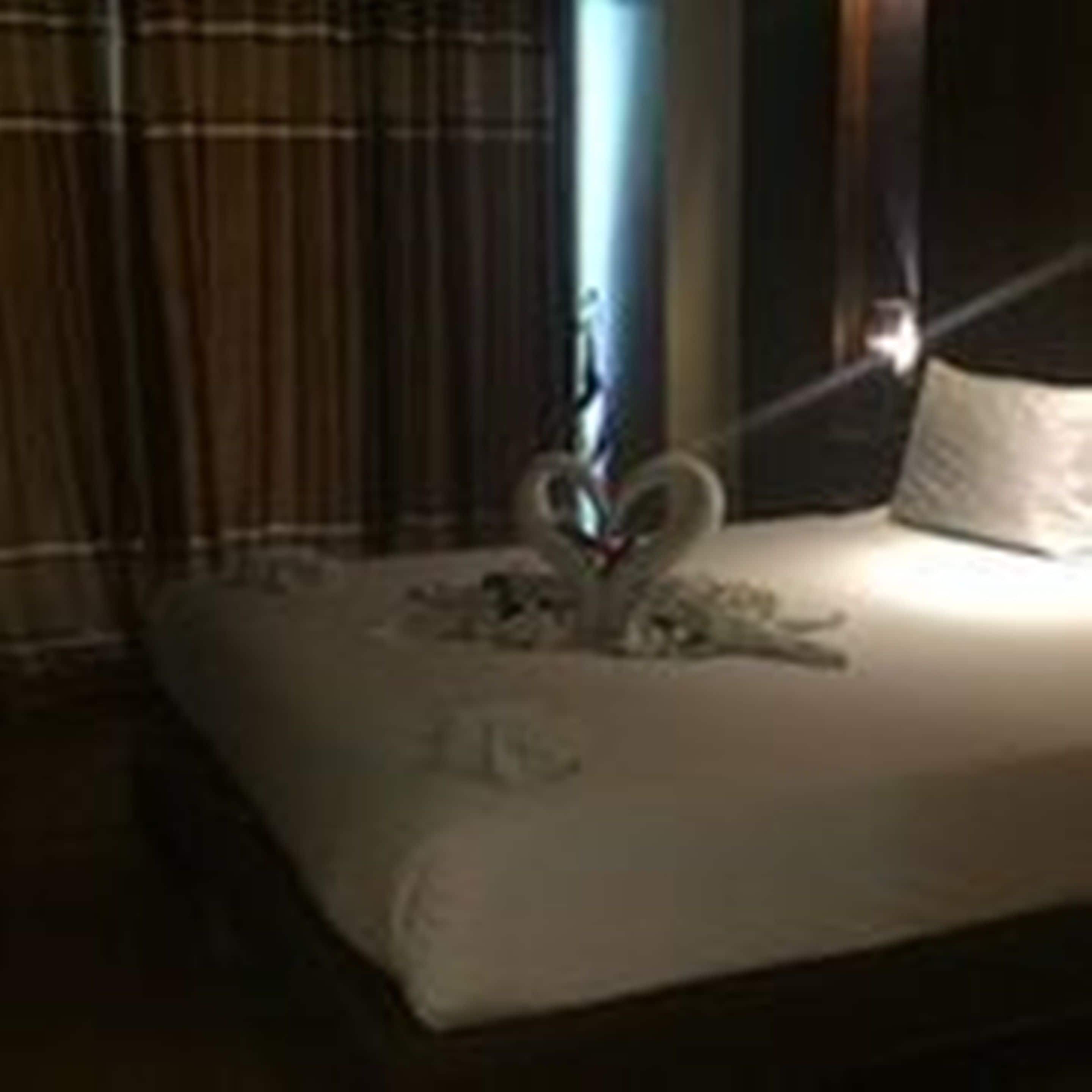 A bed with a white comforter and a decorative swan headboard.
