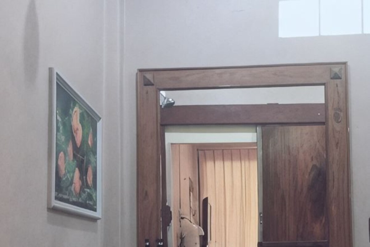 Une porte avec un cadre en bois, un tableau encadré accroché au mur et, au fond, une porte en bois.