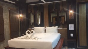 Ein Hotelzimmer mit einem ordentlich bezogenen Bett, einer herzförmigen Handtuchgestaltung und Holzvertäfelung an den Wänden.