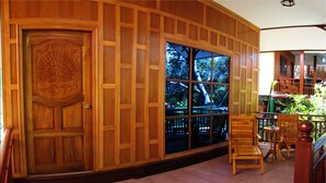 A wooden-paneled room with a large window, a door with intricate carvings, and a small table with chairs.
