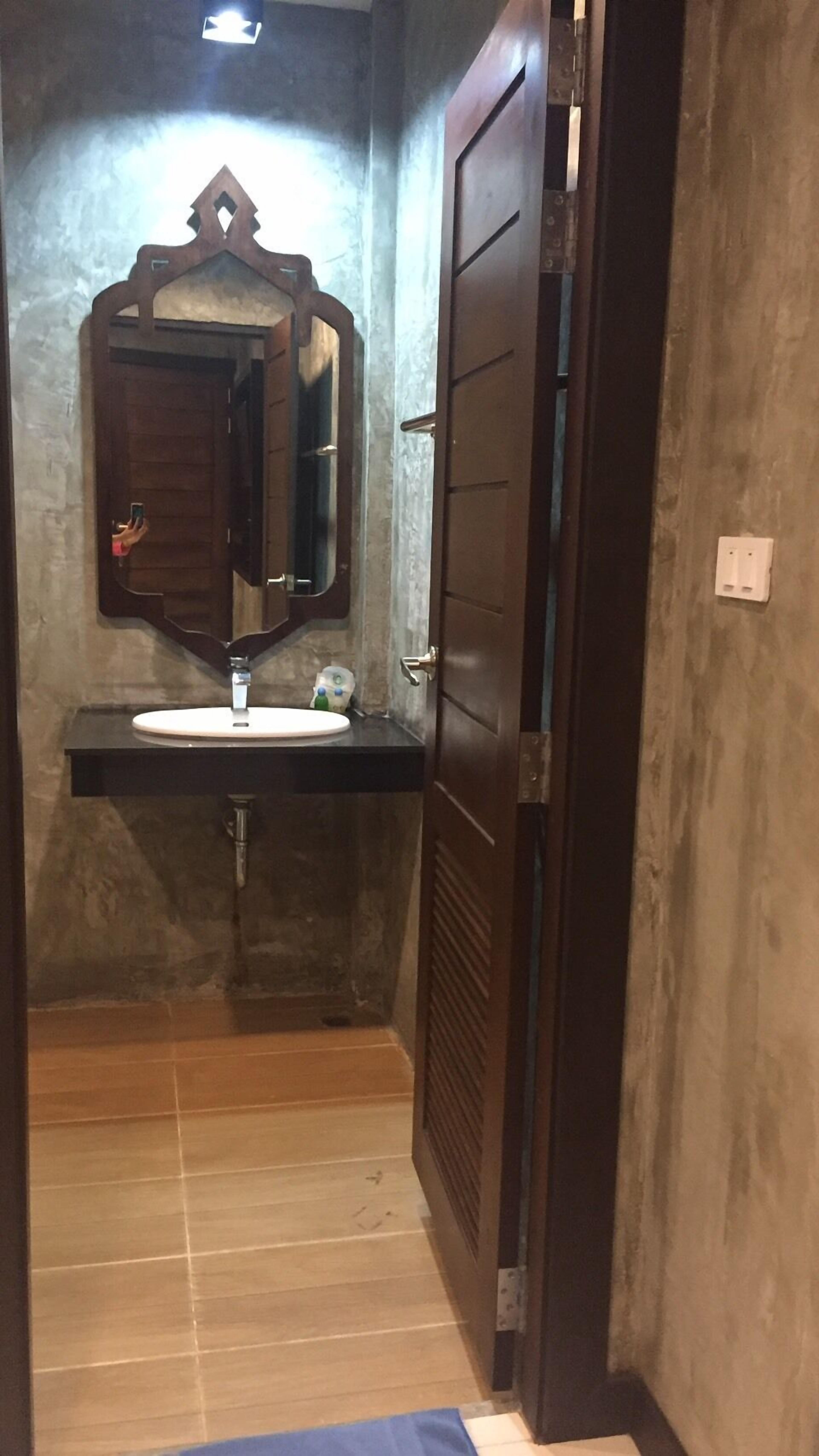 Un baño con puerta de madera, un espejo y un lavamanos.