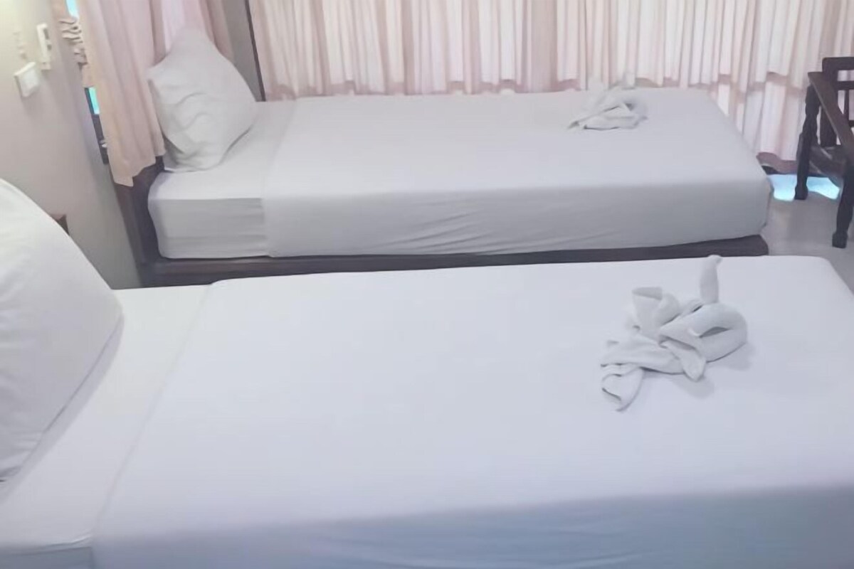 Ein Hotelzimmer mit zwei Betten, beide mit weißer Bettwäsche und ein ordentlich gefaltetes Handtuch auf einem Bett.