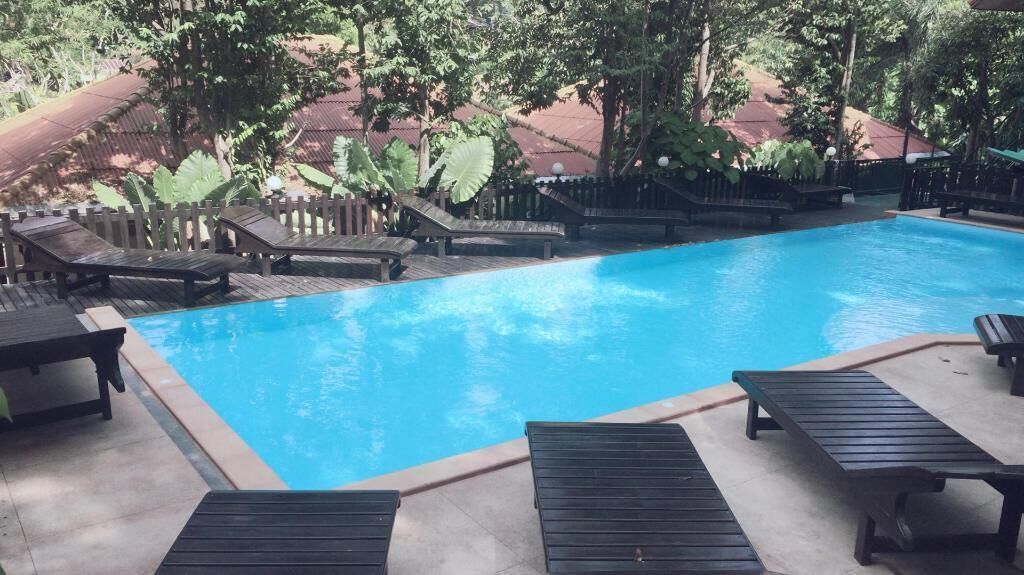 A swimming pool with lounge chairs and a wooden deck.