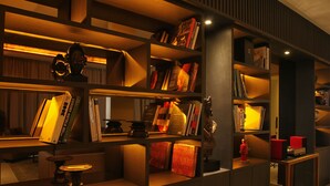 Een goed verlichte bibliotheek met boekenplanken en een tafeltje met een lamp.