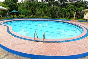 A swimming pool with a blue tiled edge, surrounded by a pinkish-brown deck. - Forest View Leisure Residences (Morong)
