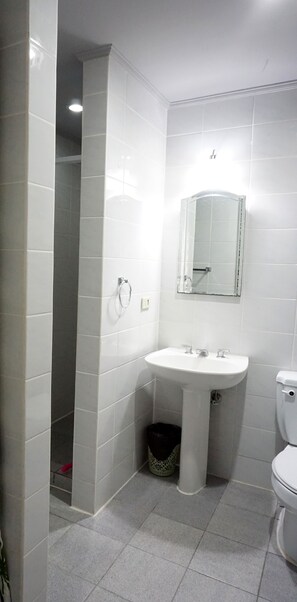 A bathroom with a white sink, a mirror, and a toilet. - Forest View Leisure Residences (Morong)