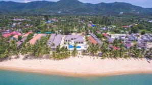 An aerial view of a coastal resort with multiple buildings, a sandy beach, and palm trees. - Shangrilah Bungalow (Koh Samui)