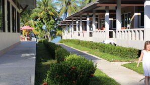 A hotel corridor with a pathway, palm trees, and a view of the sea. - Shangrilah Bungalow (Koh Samui)