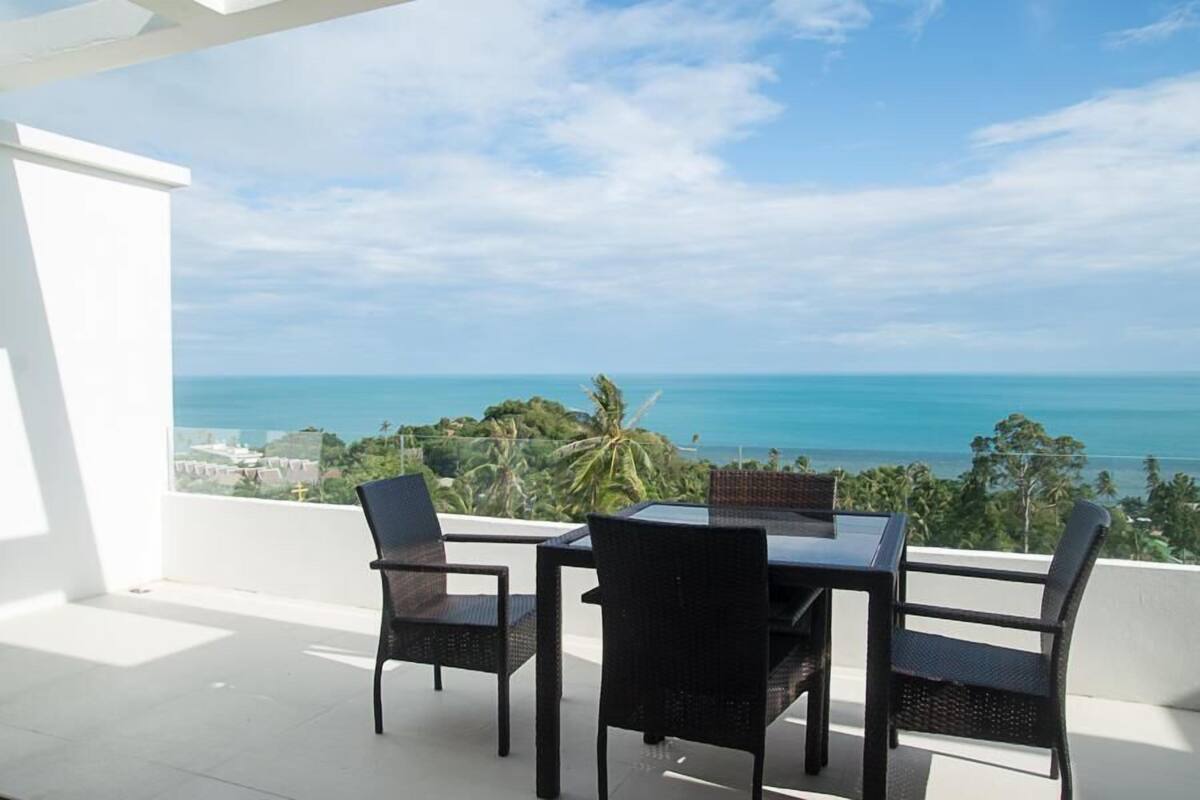 Un balcón con mesa y sillas con vistas a la costa.