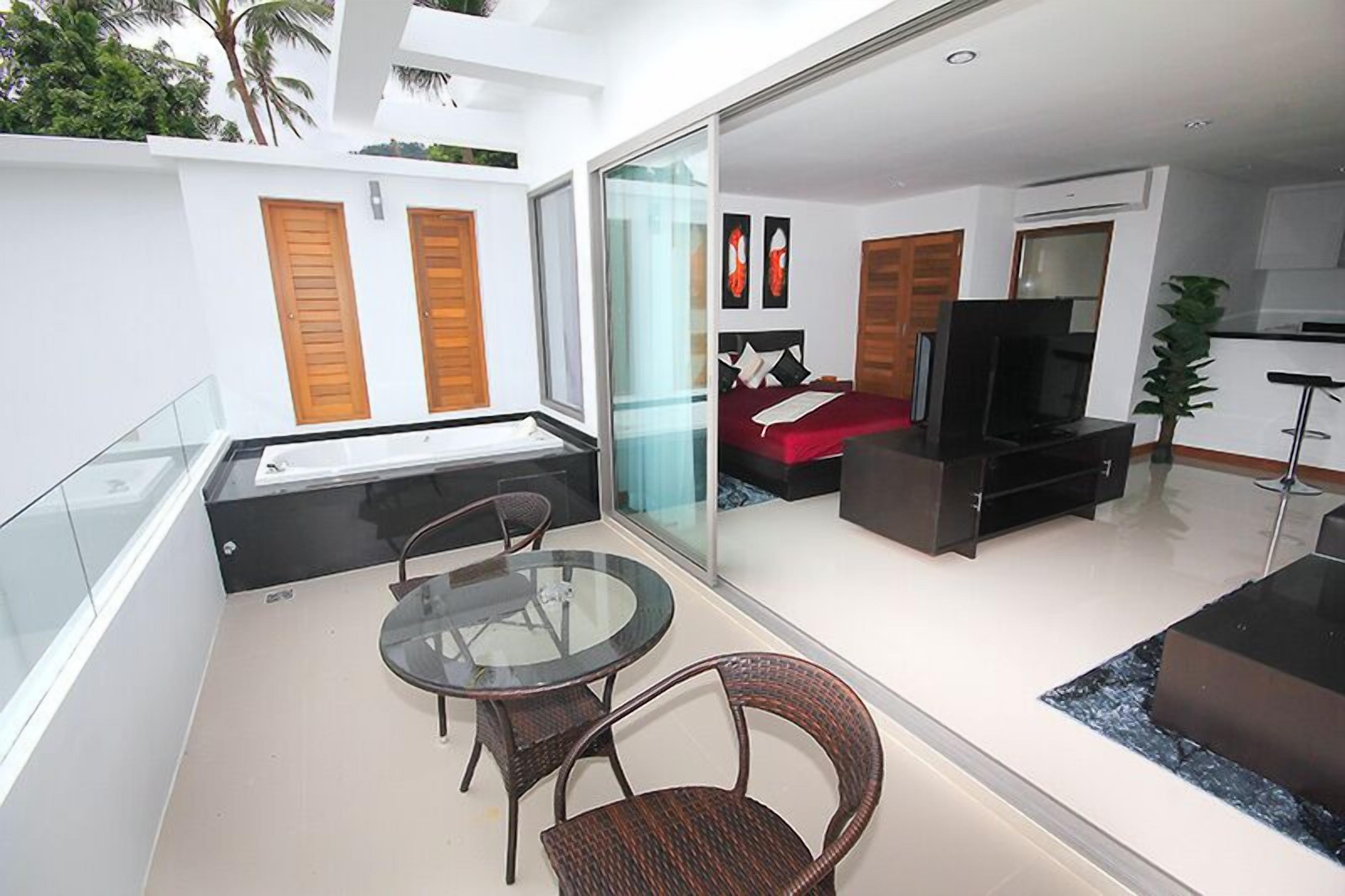 A modern living room with a glass partition, a sofa, a TV, and a dining area with chairs.