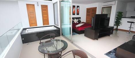 A modern living room with a glass partition, a sofa, a TV, and a dining area with chairs.