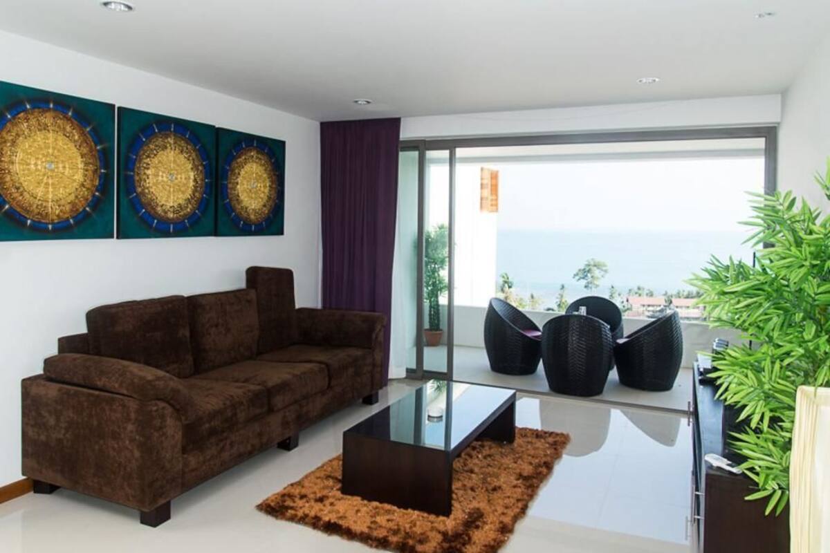 Una sala de estar moderna con un sofá marrón, una mesa de centro de vidrio y arte decorativo en la pared.