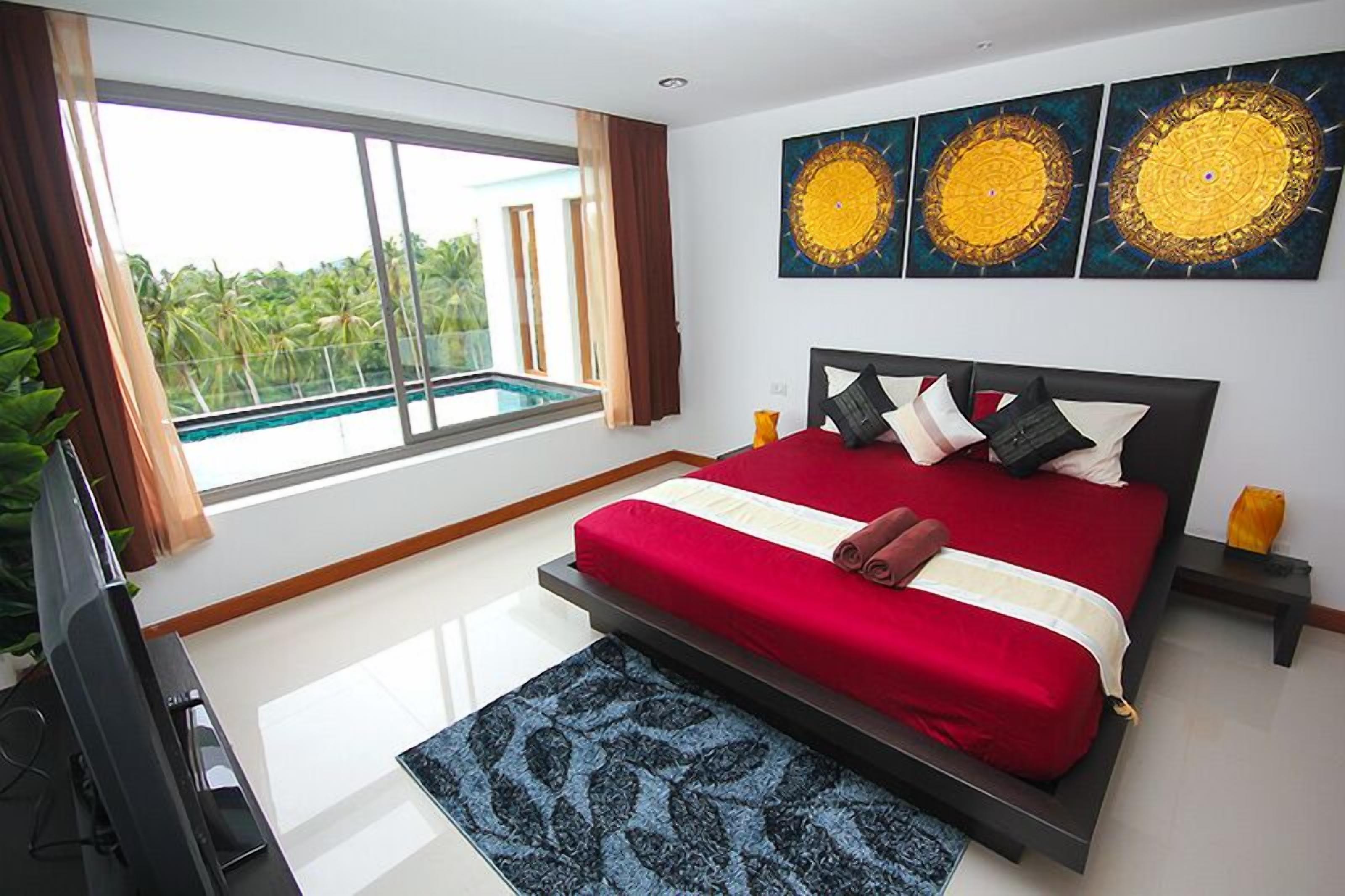 A bedroom with a large bed, a TV, a pool view, and three wall art pieces.