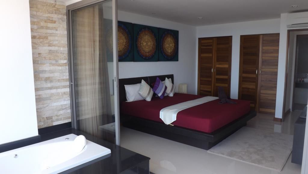 Een moderne slaapkamer met een groot bed, een douchecabine van glas en uitzicht op buiten.