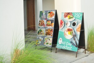 Dos carteles exteriores de menú que anuncian 'All Day Breakfast' y ofertas especiales por 250 Baht.