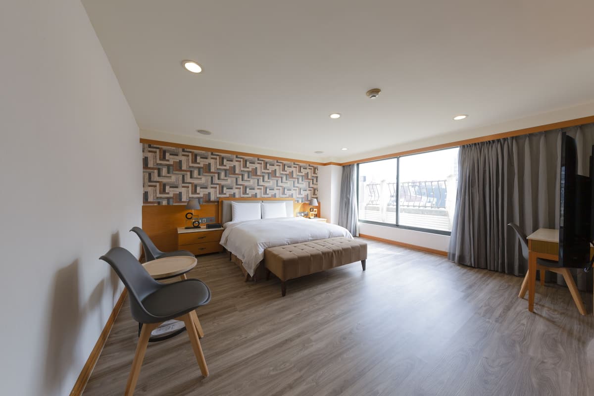 A modern hotel room with a large bed, a desk, and a chair.