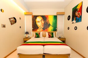 A hotel room with a bed, two nightstands, a lamp, a large painting, and wall decorations including vinyl records and a poster. - The Rhadana Kuta Bali (Kuta)