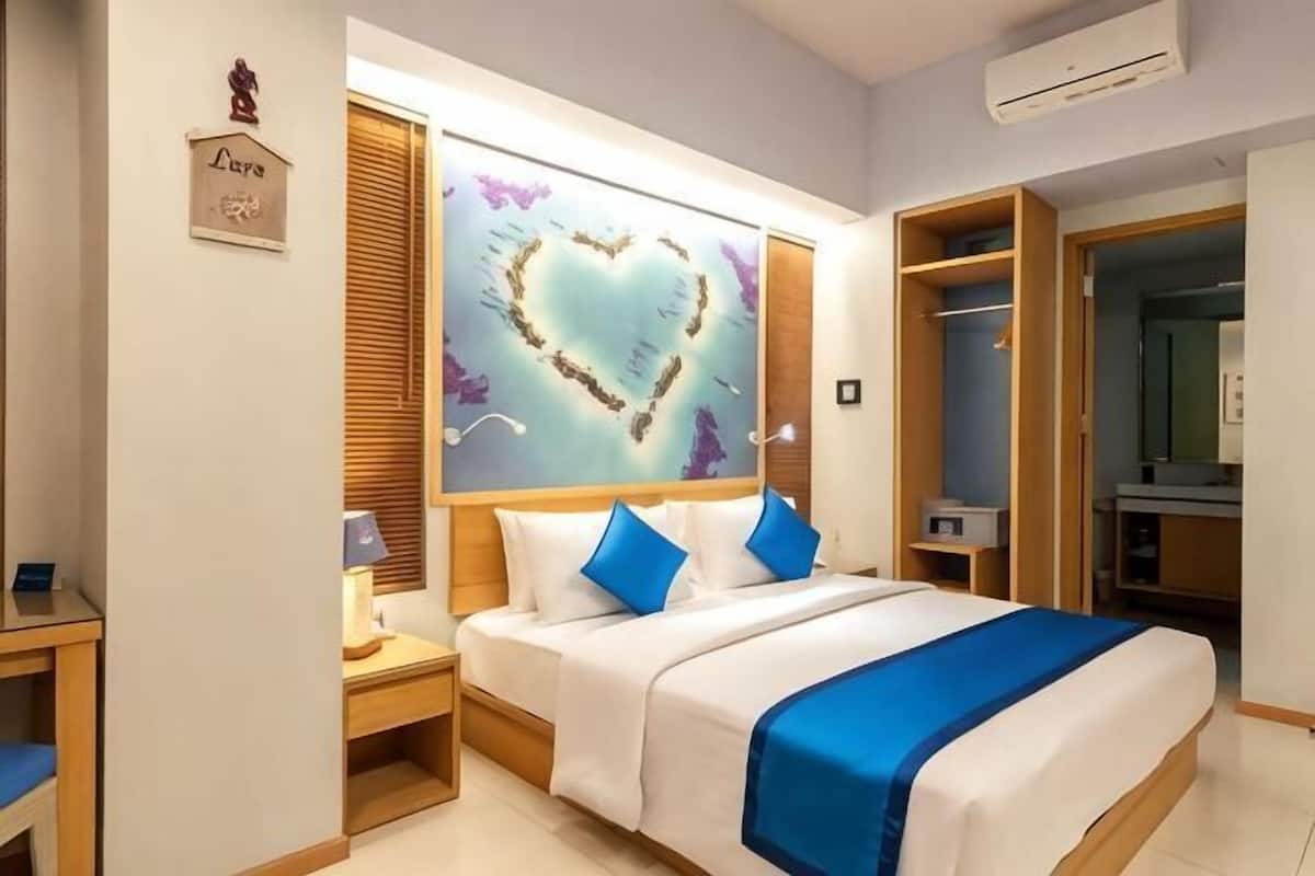 A hotel room with a bed, a nightstand, a wardrobe, and a large heart-shaped artwork on the wall.