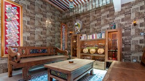 Una stanza con una panchina in legno, un tavolino da caffè e una libreria piena di libri e oggetti decorativi.