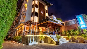 Un hotel con un cartello ben visibile, posti a sedere all'aperto e una facciata in pietra.