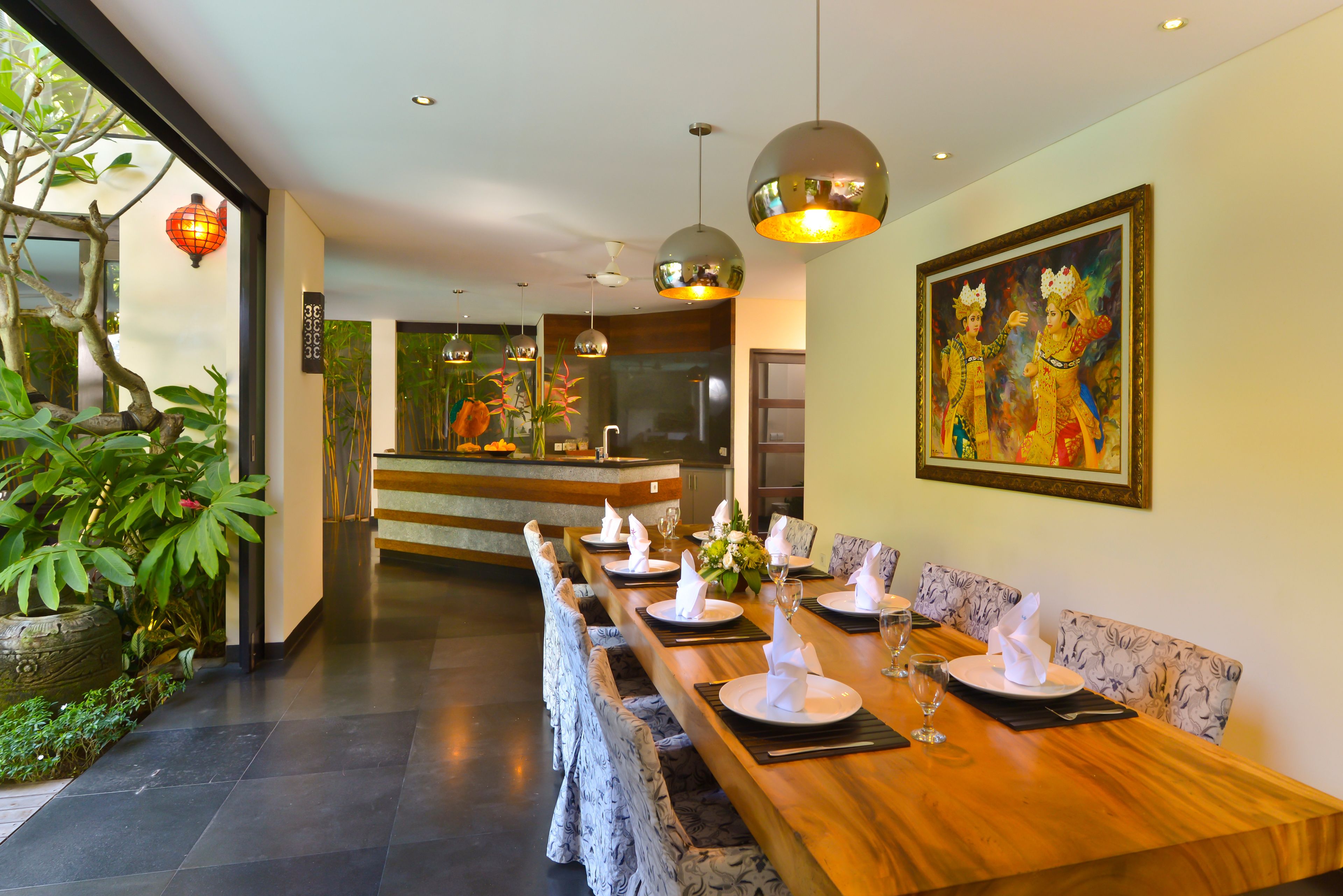 A dining area with a long wooden table set for a meal, surrounded by patterned chairs.