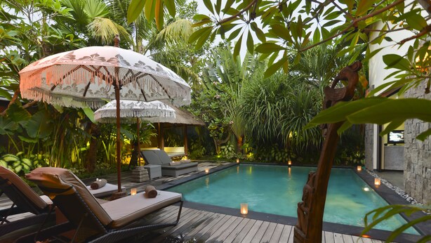 A wooden deck with lounge chairs and a pool, surrounded by lush tropical plants. - Elok Villas (Seminyak)