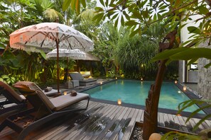 A wooden deck with lounge chairs and a pool, surrounded by lush tropical plants. - Elok Villas (Seminyak)