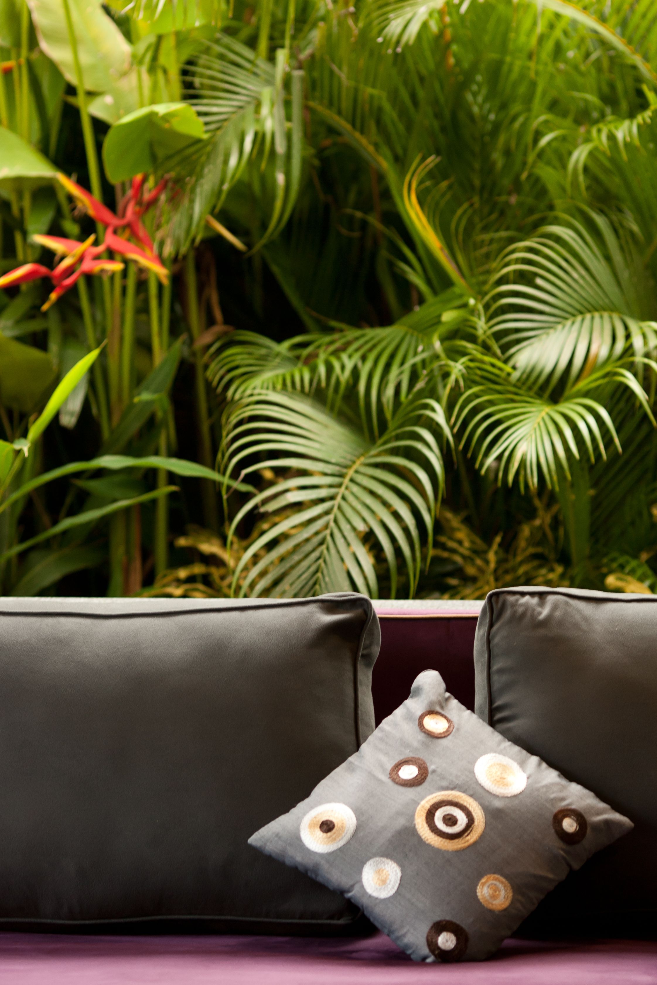 Une pièce avec un canapé de couleur sombre et un coussin décoratif orné de motifs circulaires.