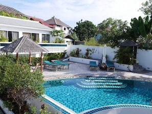 A swimming pool with a tiled edge, surrounded by lounge chairs and a small covered seating area. - Tropical Paradise Residence (Koh Samui)