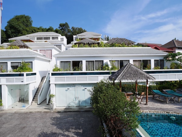 A modern hotel with a swimming pool, outdoor seating, and a staircase leading to the upper floors.