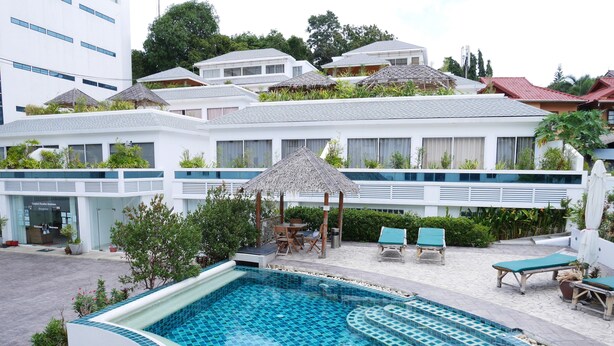 Ein Swimmingpool mit Fliesenrand, umgeben von Liegestühlen und einem Reetdach-Sonnenschirm.