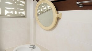 A bathroom with a round mirror, a sink, and a towel rack. - Palm Point Village (Koh Samui)