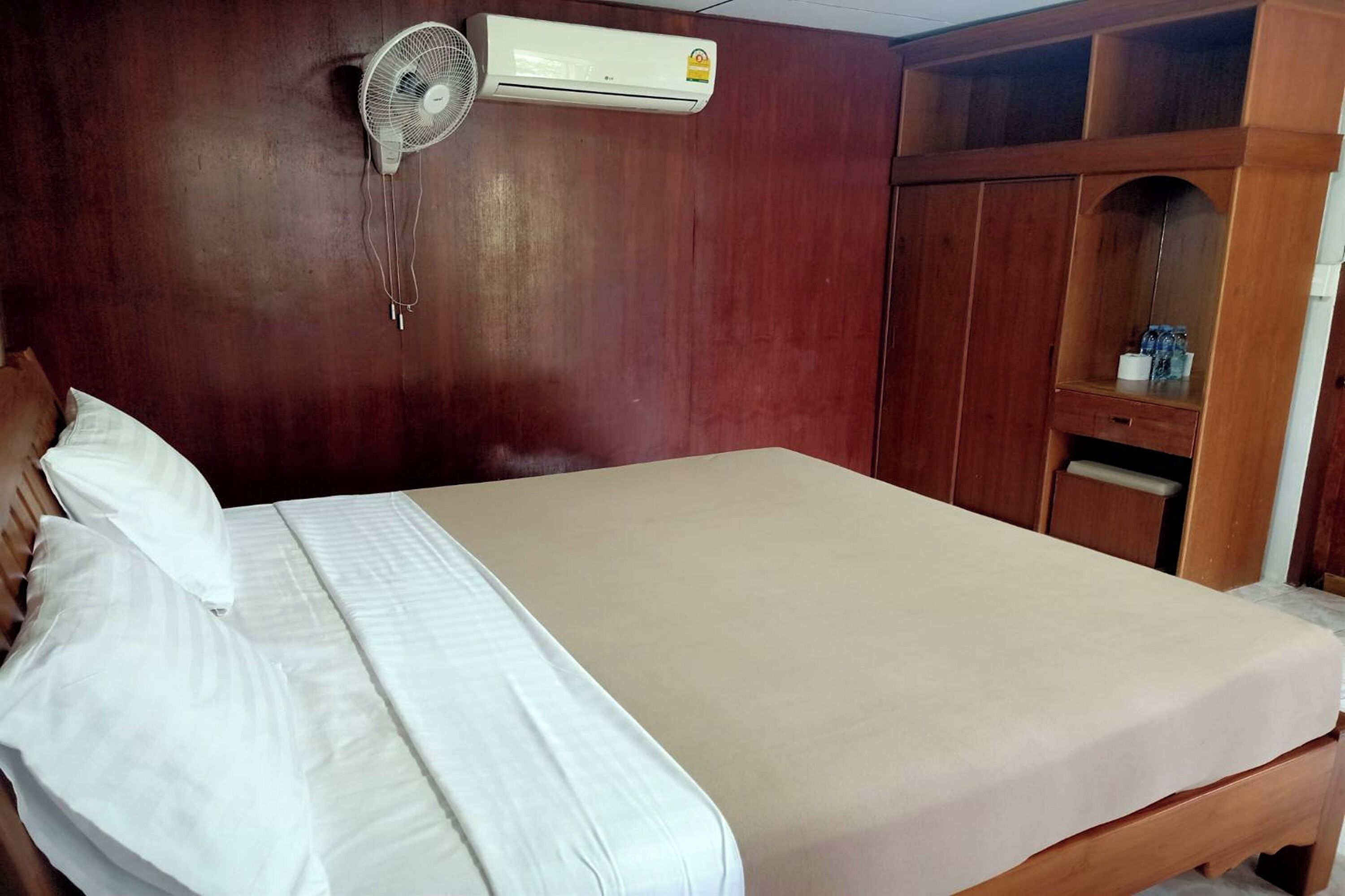 Una habitación con cama, un armario de madera y un equipo de aire acondicionado.