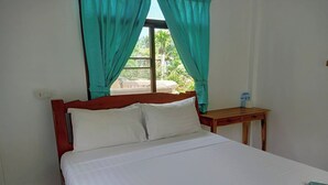 A neatly made bed with white linens, a wooden headboard, and a window with teal curtains. - Palm Point Village (Koh Samui)