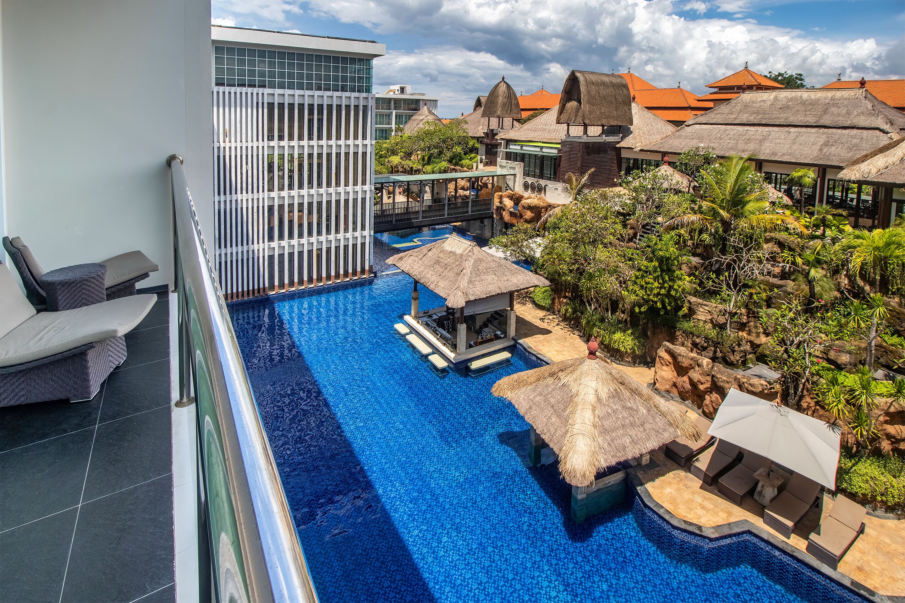 A resort pool area with a clear view of the pool, lounge chairs, and thatched umbrellas.