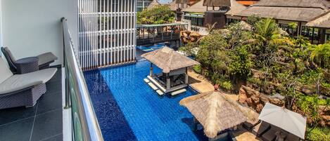 A resort pool area with a clear view of the pool, lounge chairs, and thatched umbrellas.