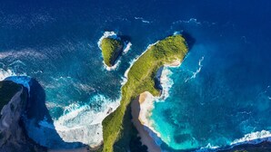 Une vue aérienne d’une zone côtière, avec deux reliefs terrestres bien distincts, entourés d’eaux d’un bleu limpide.