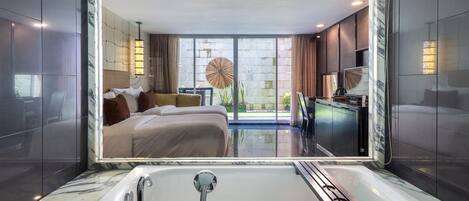 Une salle de bain moderne avec une grande baignoire, un miroir et une vue sur une chambre à coucher avec un lit et une grande fenêtre.