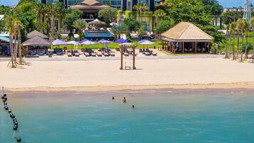 A beach resort with a pool, sun loungers, umbrellas, and a gazebo.