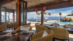 Un restaurant situé en bord de mer, avec une terrasse, une piscine et une vue sur l’océan.