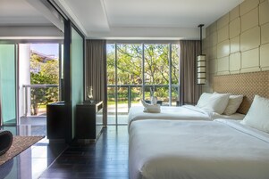 A hotel room with two beds, a large window with a view of greenery, a modern design with a tiled wall, and a balcony with a railing.