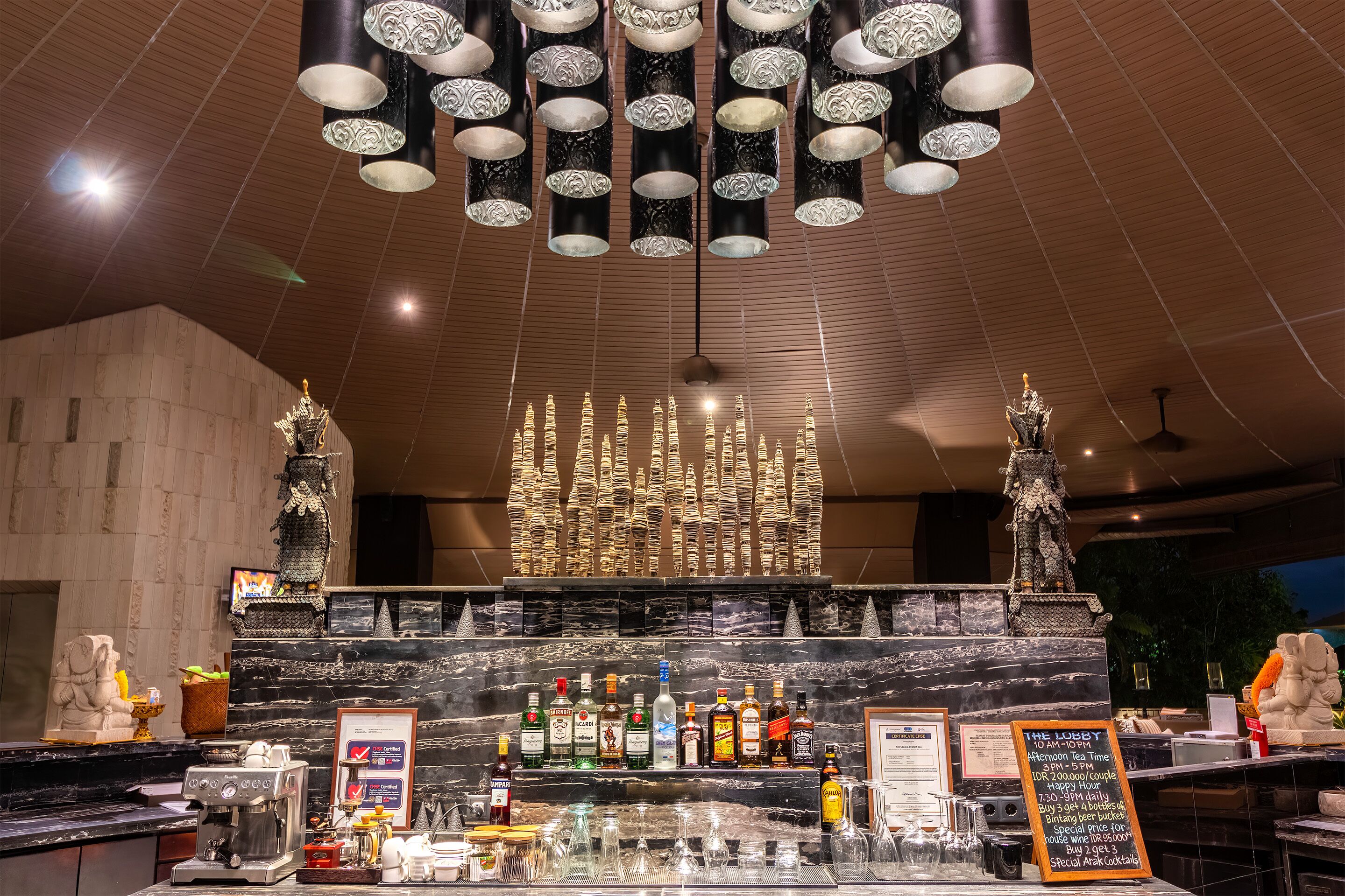 A bar area with a marble countertop, various bottles, glasses, and a menu board.