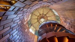 Un escalier en colimaçon avec des marches en bois et un plafond en forme de dôme de verre.